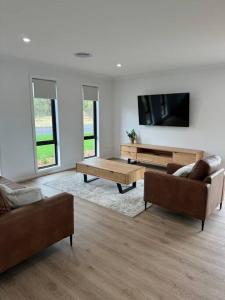 uma sala de estar com 2 sofás e uma televisão de ecrã plano em Modern luxury - Brand new home em Parkes