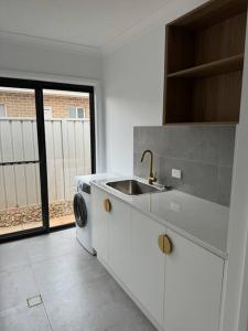 cocina con fregadero y lavadora en Modern luxury - Brand new home, en Parkes