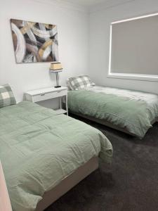 1 dormitorio con 2 camas y mesa con lámpara en Modern luxury - Brand new home, en Parkes