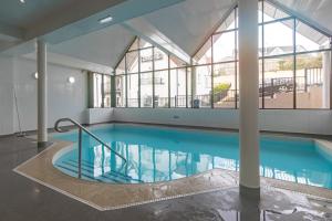 a large swimming pool in a building with a large window at Bryn Y Mor - Tenby Apartment Sea Views in Tenby