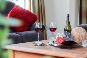 dos copas de vino tinto en una mesa de madera en Coleraine Suites & Apartments, en Greymouth