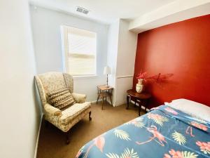 1 dormitorio con cama, silla y pared roja en Shanghai 2900 - Vintage Oriental Style 2BR w Parking near Airport, en Filadelfia