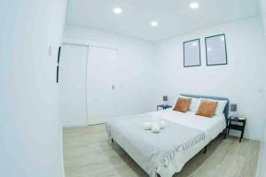 a white bedroom with a white bed with orange pillows at Bright and modern flat with air-con and free parking in Moita