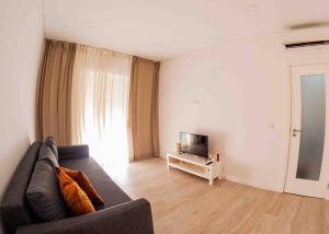 a living room with a couch and a television at Bright and modern flat with air-con and free parking in Moita