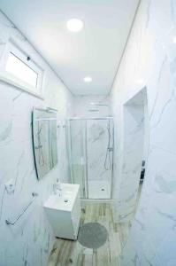 a white bathroom with a sink and a mirror at Bright and modern flat with air-con and free parking in Moita
