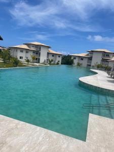 a swimming pool with blue water in front of houses at Village dos Ipês in Praia do Forte