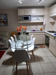 una cucina con tavolo in vetro e sedie bianche di Espectacular Depto Laguna Vista Algarrobo (3D2B) ad Algarrobo