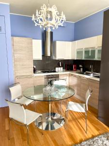 a kitchen with a glass table and white chairs at Luxury Four-Room Apartment in Monza Centro - 2 min walk to Train Station in Monza