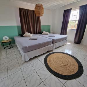 a bedroom with two beds and a rug on the floor at Nos Soño Stay and Dive in Westpunt
