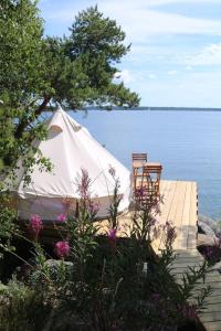 Ingmarsö的住宿－Stockholm Archipelago Retreat，座在水体旁边的码头上的帐篷