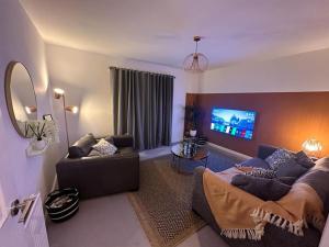 a living room with a couch and a flat screen tv at Sleek Urban Living with Bicocca Stays in Aberdeen