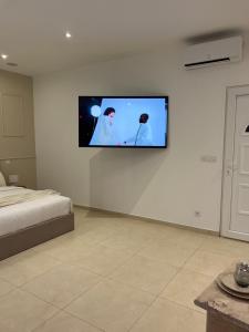 een kamer met een tv aan een witte muur bij Suite Marajah in Le Pontet