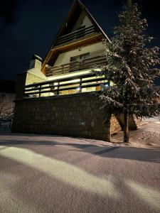 a house with a christmas tree in the snow at VillaLaylaRostovo in Bugojno