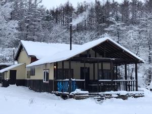 a cabin with snow on the roof of it at Bears House in Furano