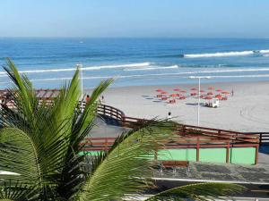a beach with umbrellas and a beach with the ocean at Apartamento Duplex na Praia Grande 108 VISTA MAR in Arraial do Cabo