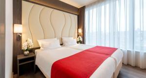 ein Schlafzimmer mit einem großen Bett mit einer roten Decke in der Unterkunft Best Western Plus Plaza Den Haag City Center in Den Haag