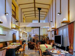 a restaurant with tables and chairs and a flat screen tv at Hotel Soyokaze in Hakuba