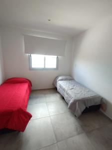 1 dormitorio con cama roja y ventana en Duplex en barrio privado en Mendoza