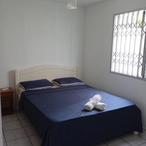 a bedroom with a bed with blue sheets and a window at Residencial Larissa Elena in Florianópolis