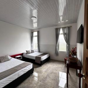 1 dormitorio con 2 camas y TV. en Apartamento Familiar Buga - Basílica señor de los milagros N1 en Buga