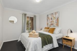a white bedroom with two beds and a window at NORM3/17 - Little Hacienda in Perth