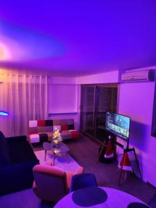 パリにあるAppart'Chicの紫色の照明とテレビ付きのリビングルーム