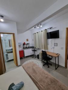 a room with a bed and a desk and a kitchen at Studio fantástico in São Paulo