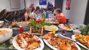 Island Accommodation Suva Premier Hospitality في سوفا: مجموعة من الناس يجلسون على طاولة طويلة مع الطعام
