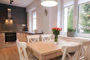 a kitchen with a wooden table and white chairs at Apartment Schober - Rezidence K Lanovce in Jáchymov +13 photos