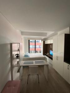 a white bedroom with a bed and a table at Apartamento grande Soho 39 in Bogotá
