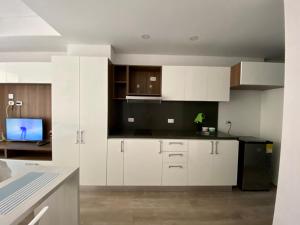 a kitchen with white cabinets and a black refrigerator at Apartamento grande Soho 39 in Bogotá