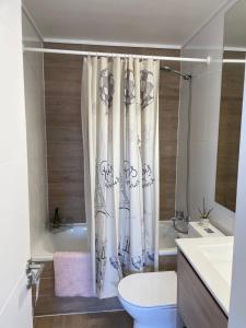 a bathroom with a toilet and a shower curtain at Departamento con piscina vista panorámica in Coquimbo +19 photos