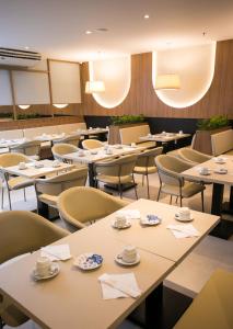 un comedor con mesas y sillas con tazas. en Regency Park Hotel - SOFT OPENING en Río de Janeiro