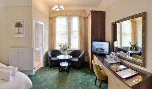 a hotel room with a desk and a mirror at Cavendish Central Bournemouth in Bournemouth