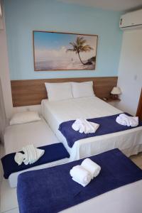 two beds in a hotel room with towels on them at Flat Studio aconchegante com vista para piscina. in Ipojuca
