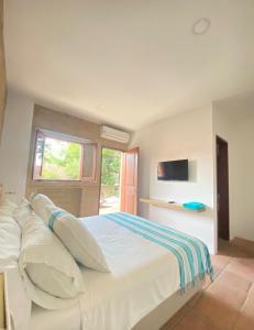 a bedroom with a large white bed with a window at Hotel San German in Girardot
