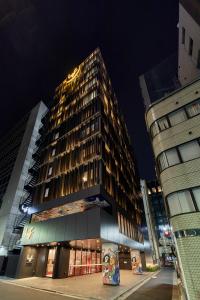 a tall building at night with two tall buildings at lyf Ginza Tokyo in Tokyo