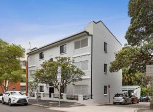 un edificio bianco con macchine parcheggiate di fronte di Hamilton Lodge a Sydney