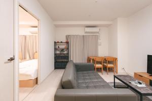 uma sala de estar com um sofá e um quarto em 谷町君ホテル　難波80 em Osaka