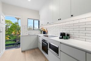 a kitchen with white appliances and a large window at Hamilton Lodge in Sydney