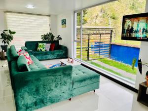 a living room with a green couch and a window at CASA VISTA HERMOSA in Baños