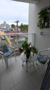 uma varanda com cadeiras, uma mesa e uma planta em Apartamento 2 quartos na praia em Florianópolis