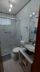 uma casa de banho com um chuveiro, um WC e um lavatório. em Apartamento 2 quartos na praia em Florianópolis