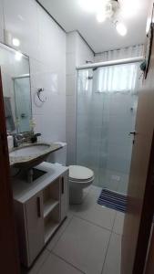uma casa de banho com um WC, um lavatório e um chuveiro em Apartamento 2 quartos na praia em Florianópolis