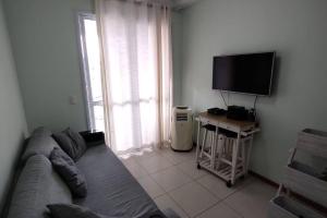 uma sala de estar com um sofá e uma televisão de ecrã plano em Apartamento 2 quartos na praia em Florianópolis