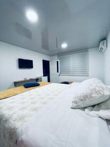 1 dormitorio con 1 cama blanca grande y TV en Posada Jimmy S House, en San Andrés