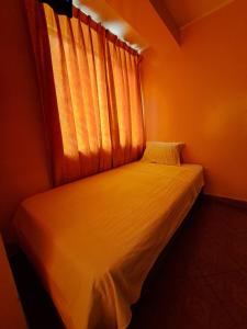 Cama pequeña en habitación con ventana en Hospedaje Leo en Lima