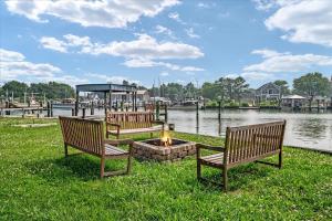two benches sitting next to a fire pit next to the water at Waterfront Bliss- Ultimate Tilghman Retreat home in Tilghman +42 photos