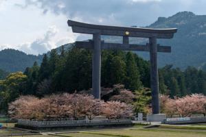 una puerta torii gigante en un parque con árboles en KANAU, en Gojō