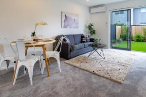 een woonkamer met een tafel en een bank bij Upper Riccarton dream - 2 bed 2 bath w/carpark in Christchurch